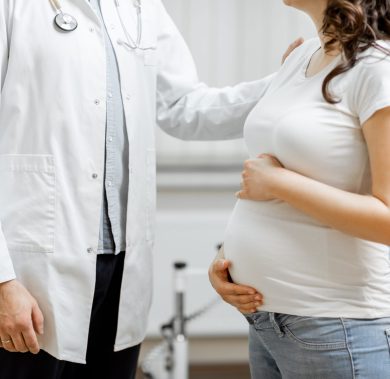 Doctor with a pregnant woman in the office, cropped view without face. Concept of medical care and health during a pregnancy