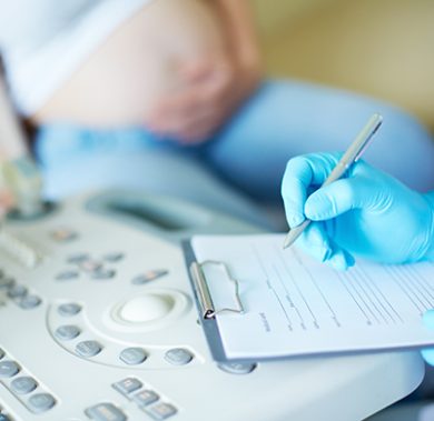 Gloved hand of obstetrician making notes during regular examination at hospital