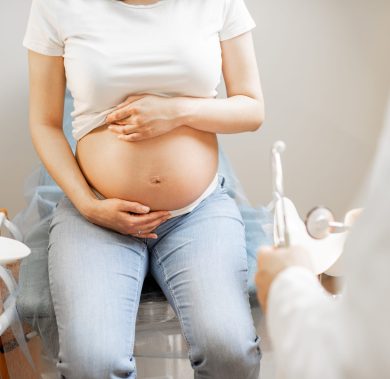 Pregnant woman on a gynecological chair during a medical examination, cropped view without face focused on abdomen