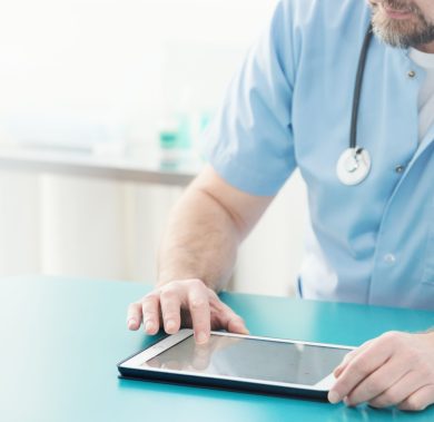 Close-up of doctor with stethoscope using tablet during work