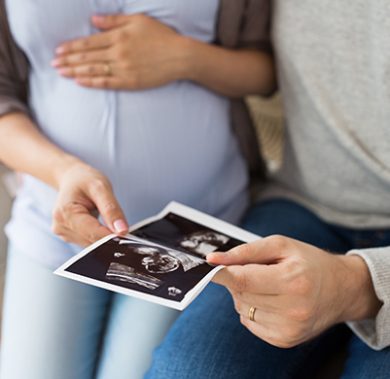 pregnancy, family and people concept - close up of man with his pregnant wife looking at baby ultrasound images at home